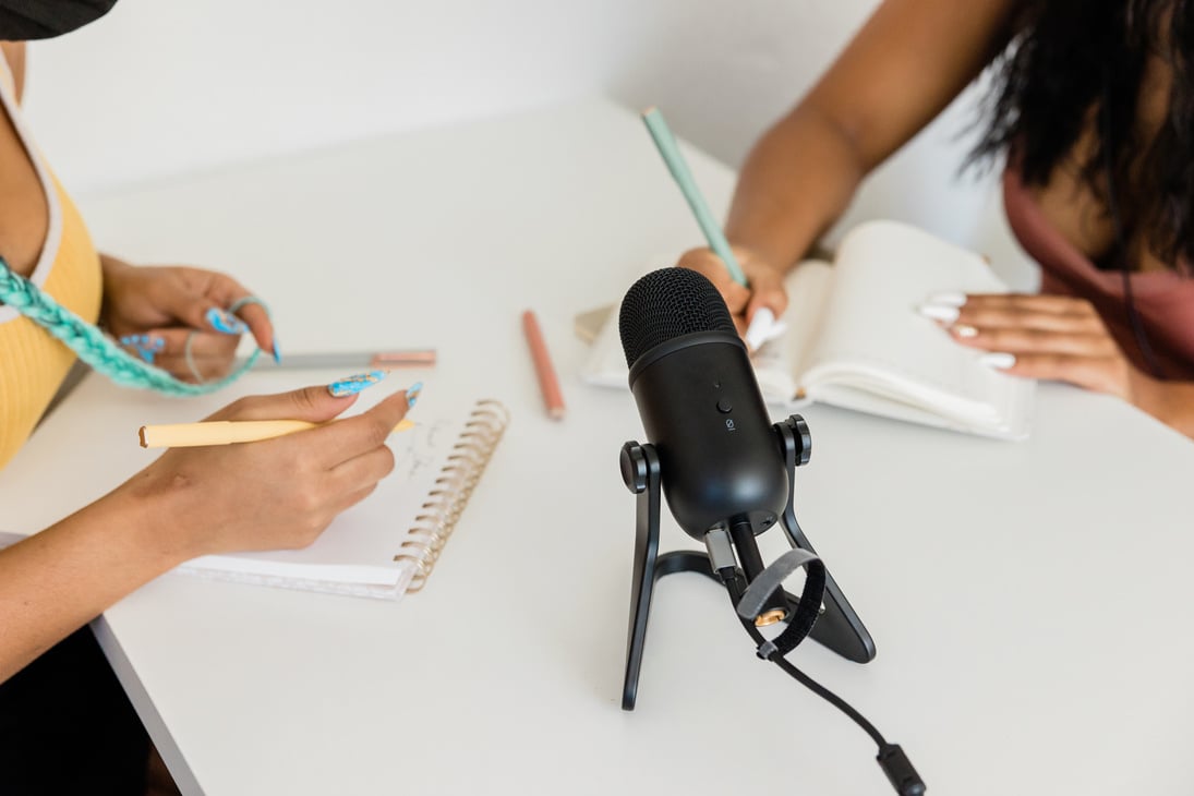 Women Writing Notes While Recording a Podcast